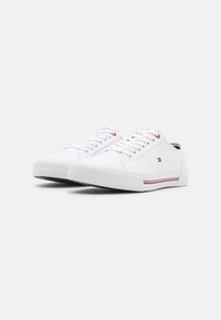 Sneakers bianchi in tela dal design low-profile, con righe di accento rosse e blu, punta rotonda e suola in gomma testurizzata.