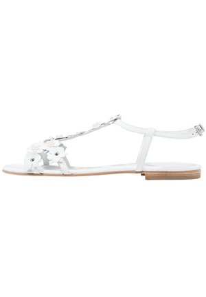 Witte platte sandaal met enkelband en decoratieve witte bloemen en parelmoeren kralen op de voorkant van de T-band.