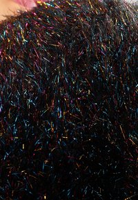 Tela negra texturizada con hilos metálicos multicolores en azul, dorado y rosa. El material parece esponjoso y brillante.