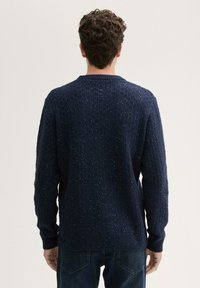 Marineblauwe gebreide trui met een textuurpatroon en geribbelde manchetten. Heeft een ronde halslijn en een ontspannen pasvorm. Gemaakt van zacht, dik garen.