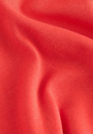 Koraljna pamučna tkanina s glatkom teksturom, koja sadrži meke nabore i ravnomjerno pleten uzorak. Lagana i blago rastezljiva.