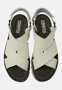 Sandale din piele gri deschis, cu barete încrucișate, curea ajustabilă pe spate și o branț negru cu sigla "CAMPER". Design plat, minimal.