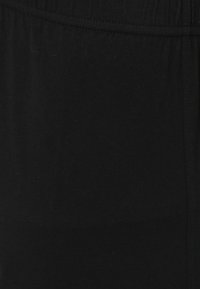 Zwarte stof met een gladde textuur en een elastische tailleband, met een eenvoudig, onopgesmukt ontwerp zonder zichtbare patronen of accenten.