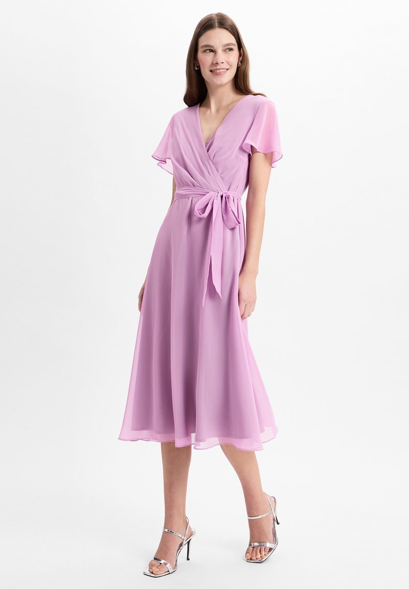 Hellblaues Kleid mit kurzen, flatternden Ärmeln, V-Ausschnitt, tailliertem Bund und fließendem Rock; getragen mit silbernen Strappy-High-Heels.