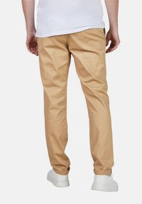 Beige Hosen mit geradem Schnitt, aus Baumwollmischung. Mit Gesäßtaschen, umgeschlagenen Säumen und kombiniert mit weißen Sneakers.