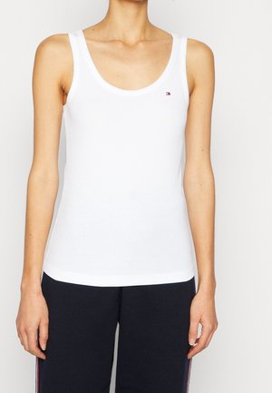 Débardeur blanc en tissu côtelé. Il présente un col arrondi et un petit logo sur le côté gauche de la poitrine. Design à ourlet droit.