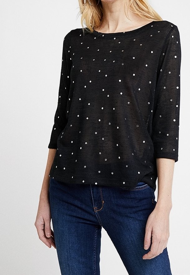 Svart topp med trekvartslånga ärmar, gjord av lättviktig tyg, med silverprickar som är jämnt fördelade över ytan.