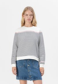 Witte en marineblauwe gestreepte sweatshirt met een ronde halslijn en geborduurde rode tekst. Gepaard met een denim rok met knopen aan de voorkant.