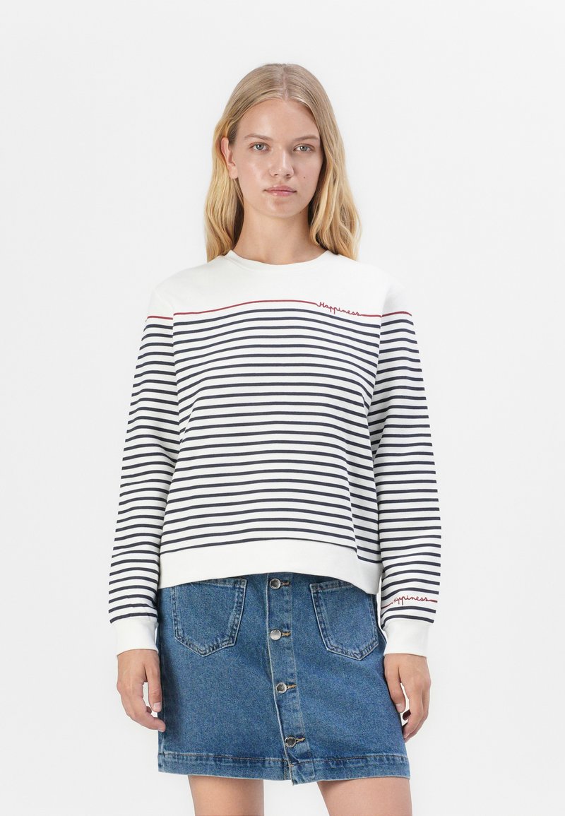 Witte en marineblauwe gestreepte sweatshirt met een ronde halslijn en geborduurde rode tekst. Gepaard met een denim rok met knopen aan de voorkant.