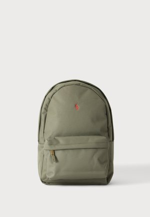 Grüner Rucksack mit einer vorderen Reißverschlusstasche und einem kleinen roten gestickten Logo, das in der Nähe der Oberseite zentriert ist.