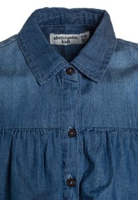 Jeanshemd in Blau mit Hemdkragen, Knöpfen vorne und gerafftem Stoff an der Taille. Etikett zeigt die Größe 9/10 an.