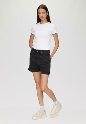 White short-sleeve ribbed t-shirt paired with black denim shorts. Shorts have rolled cuffs, displayed with light-colored platform sneakers.