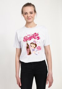 Vit bomull t-shirt med en färgglad retrografik av en läskflaska och en tecknad karaktär, med rosa och röda texter och stjärnor.