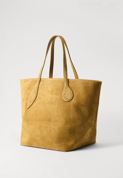 Sac fourre-tout en suède jaune avec deux longues anses, une texture lisse et un design minimaliste, présentant des bords arrondis et sans matériel visible.