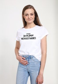 Vit bomulls t-shirt med svart text: "Marvel Studios Doctor Strange in the Multiverse of Madness." Kortärmad, avslappnad passform.