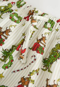 Pantaloni corti di cotone con elastico in vita, caratterizzati da una stampa festiva del Grinch, motivi natalizi e accenti rossi e verdi su uno sfondo a strisce.