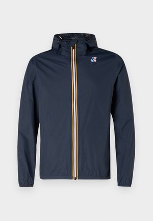 Marineblå hættejakke med stribet gul, hvid og orange lynlås og lille logo på venstre bryst, vist på ensfarvet baggrund.