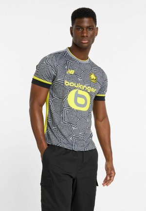 Gray patterned short-sleeve sports jersey with yellow accents and logo, featuring geometric designs and a round neckline. Black shorts are worn.