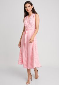 Różowo-biała, w paski, bezrękawnikowa sukienka z zak ładanym fasonem, związywana w talii i zwiewnym dołem, wykonana z lekkiego materiału.