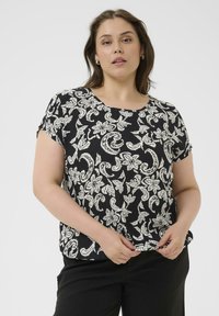 Zwarte blouse met korte mouwen en een wit, bloemen- en paisleypatroon, ronde hals, nauwsluitende pasvorm en zachte, getextureerde stof. Gecombineerd met een zwarte broek.