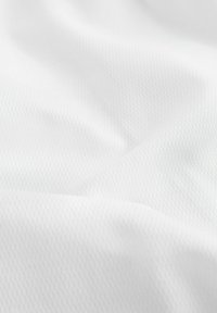 Fehér, texturált szövet finom, gyémántmintával. Puha, sima felülete könnyűnek tűnik és lágyan omlik, diszkrét fénylással.