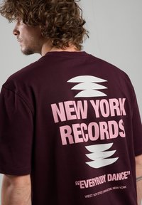 Maroon t-shirt featuring a large pink graphic text reading "NEW YORK RECORDS" and "EVERYBODY DANCE," with a white abstract design above.