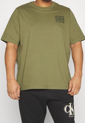 T-shirt en coton vert olive avec un col rond, des manches courtes et une petite impression de logo noir sur la poche gauche. Texture lisse.