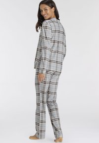 Set di pigiama a quadri grigi composto da una maglia con bottoni e pantaloni dritti, realizzato in un tessuto morbido con sottili linee a contrasto beige e nere.