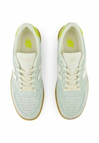 Ljusblå mockasneakers med perforerat mönster, vita detaljer, beige snören och en gummisula. Grön logotyp på innersulan.