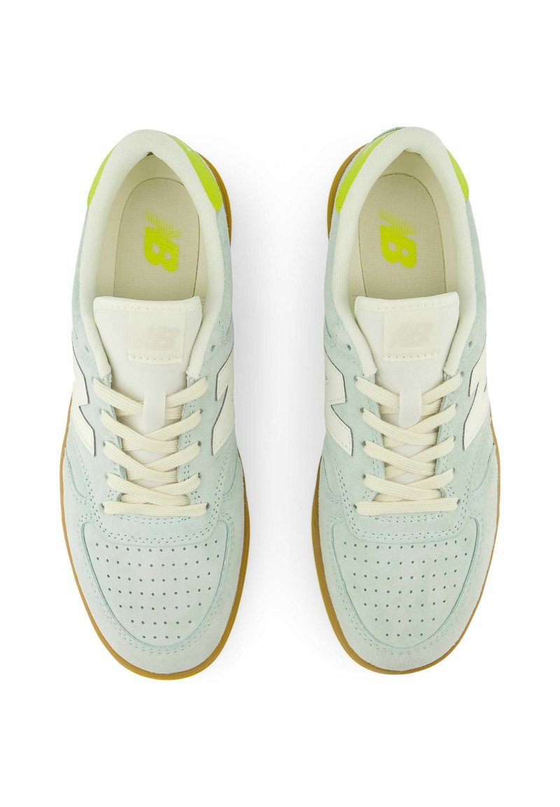 Zapatillas de ante azul claro con diseño perforado, acentos blancos, cordones beige y suela de goma. Logotipo verde en la plantilla.