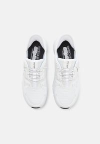 Baltos sportinės bateliai su tamprių akių viršumi, plonomis raišteliais ir juoda pado dalimi su užrašu "SKECHERS". Tekstūruotas guminis padas ir struktūrizuota konstrukcija.