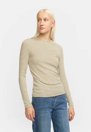 Haut ajusté à manches longues avec des rayures horizontales vert olive et crème. Tissu lisse, col rond, associé à un jean bleu, modèle se tenant devant un fond neutre.