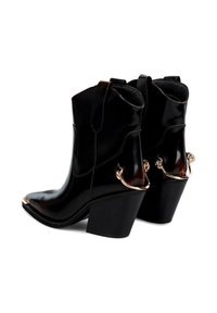 Botas de tobillo de charol negro con punta afilada, tacón cuadrado alto y acentos de hardware dorado en el tobillo. Textura suave, diseño elegante.