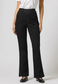 Pantalones acampanados negros de tela vaquera, con una cintura alta y diseño de cinco bolsillos. Textura suave y bajos rematados.