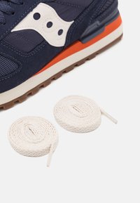 Navy sneakers med teksturert øvre, hvite detaljer, oransje mellomsåle og to rullede bomullssnører i lys beige.