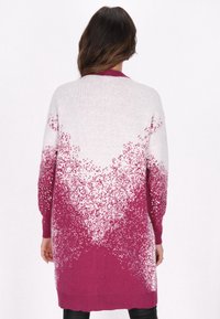 Maglione lungo in gradiente da bianco a bordeaux, con decorazioni argentate sulle maniche. Tessuto lavorato a maglia con polsini e orlo a costine.