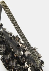 Sort pailletbesat håndtaske med en tekstureret, skinnende overflade. Har et dekorativt perlehåndtag og en lynlåsåbning.