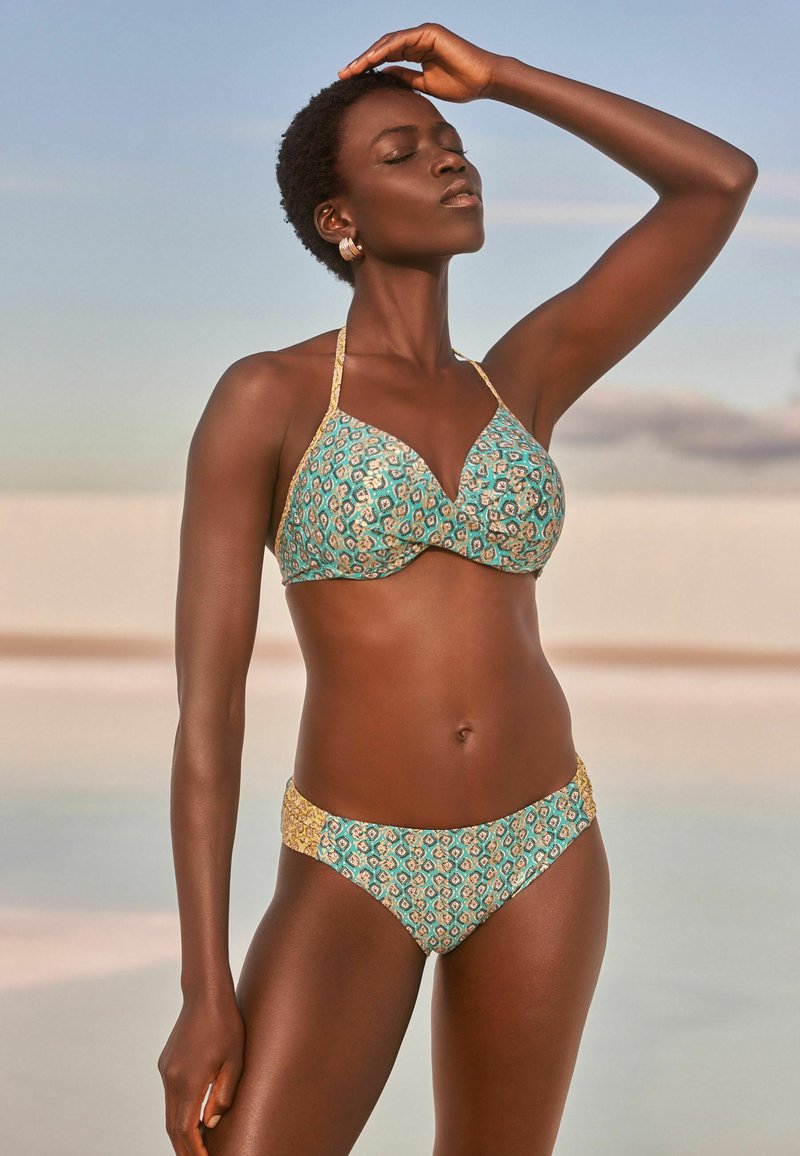 Bikini set s tirkiznim i zlatnim uzorkom. Halter top s oblikovanim čašama i donji dio s niskim strukom koji ima sličan dizajn i teksturu.