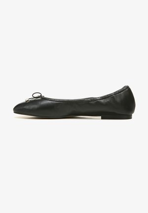 Bailarina de cuero negro con punta redondeada, que presenta un pequeño lazo decorativo y una suela de goma delgada y plana. Textura suave y diseño minimalista.