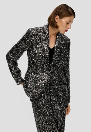 Blazer noir à paillettes avec manches longues, col châle et poches avant. Le tissu est brillant, créant une apparence texturée et scintillante.