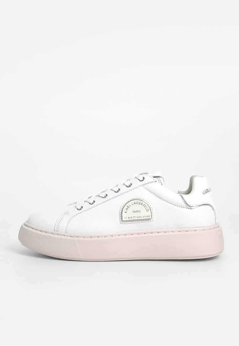 Zapatillas de piel blanca con punta redonda, suela plana de goma beige, cordones en la parte delantera y un parche de logo en el lateral. Textura suave, diseño minimalista.
