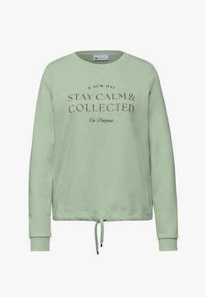 Jasnozielona bluza z długimi rękawami, okrągłym dekoltem i regulowanym sznurkiem w talii. Posiada nadrukowany tekst w ciemnych i jasnych odcieniach.