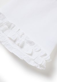 Weißer Baumwollstoff mit einer gerafften Saumkante, weichen, strukturierten Rüschendetails, die einen schichtartigen Effekt erzeugen. Einfaches und sauberes Design.
