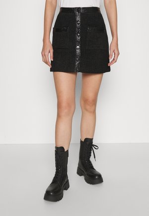 Minigonna nera con texture, quattro tasche e chiusura frontale con bottoni, abbinata a stivali combat neri con design con lacci e suole spesse.