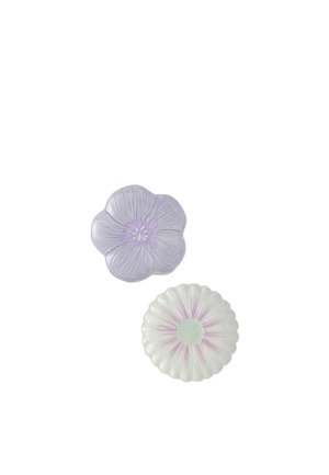 To dekorative keramiske tallerkener formet som blomster, den ene lyse lilla med fem kronblade og den anden hvid med pink accenter og bølgekant.