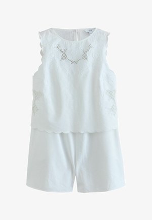 Hvid ærmeløs top med blomsterblonde og bølgede kanter kombineret med matchende hvide shorts.