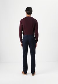 Cămașă burgundy cu mânecă lungă, pantaloni bleumarin și încălțări maronii. Design simplu, formă ajustată și detalii minime, cu o textură netedă.