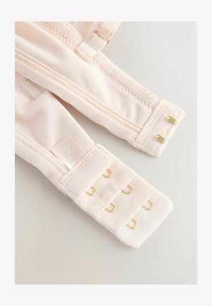 Rožinės spalvos audinio liemenėlės petnešėlė su minkšta tekstūra, su aukso spalvos metaliniu reguliavimo ir užsegimo mechanizmu. Petnešėlėje yra logotipo etiketė.