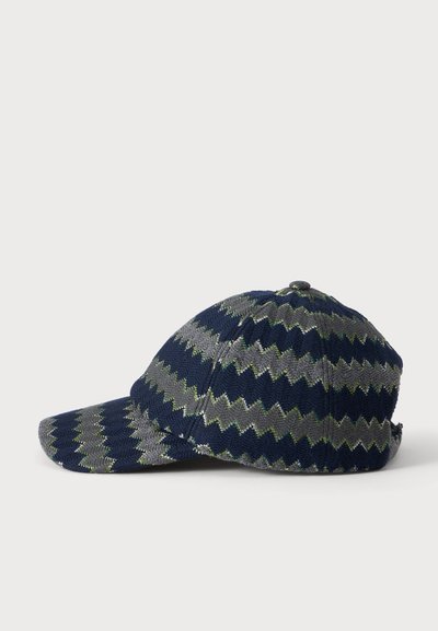 Casquette de baseball en tissu à motif zigzag bleu marine et gris, avec une visière incurvée et un bouton sur le dessus, vue de côté sur fond blanc.