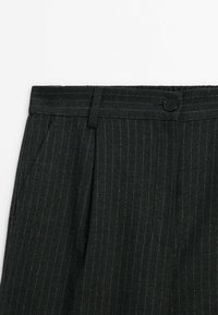 Pantalon gris foncé avec des rayures verticales, fabriqué en tissu texturé, doté d'une fermeture à bouton, passants de ceinture et poches latérales.